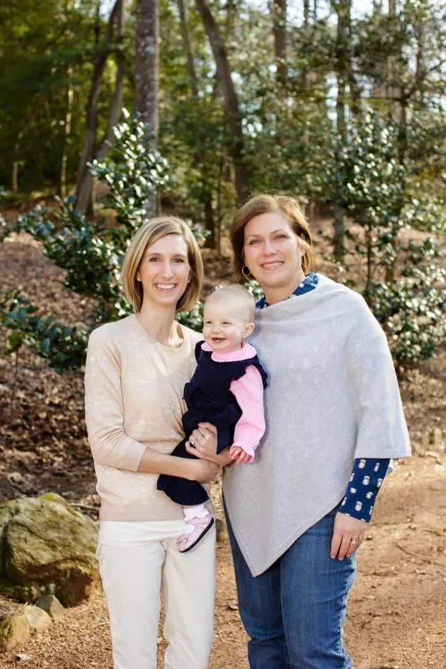 Emily holding Ellie on a wooded trail with a family member