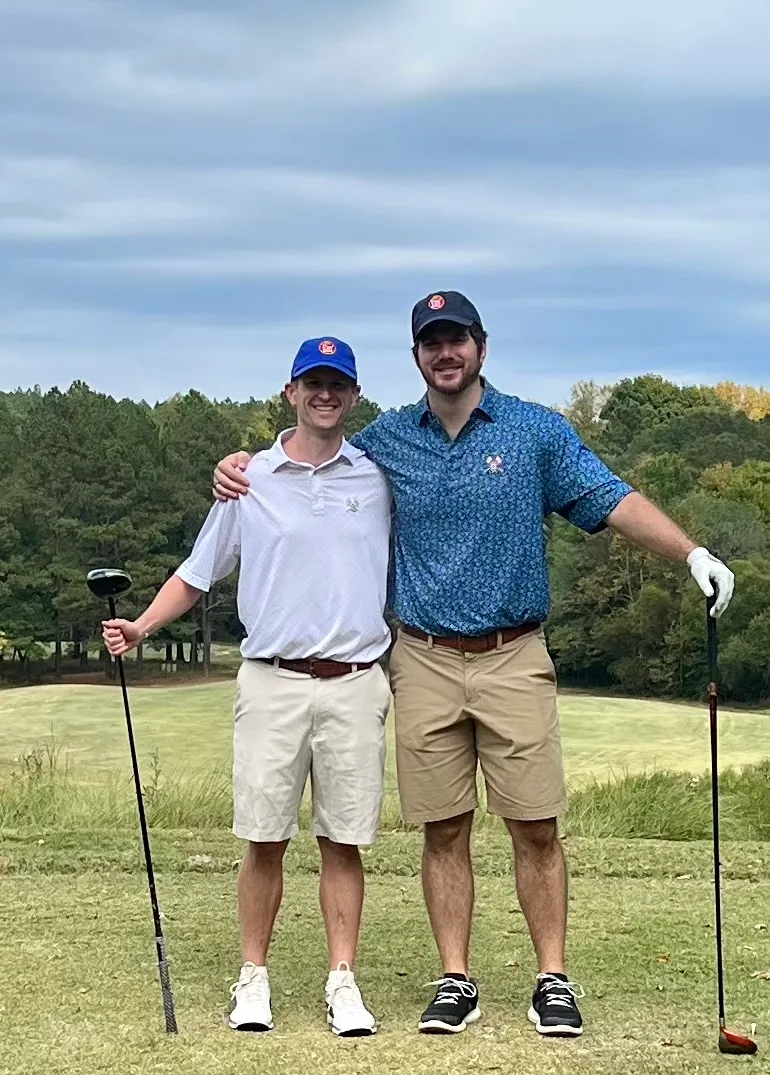 Two golfers posing on the course at a past Em’ tournament